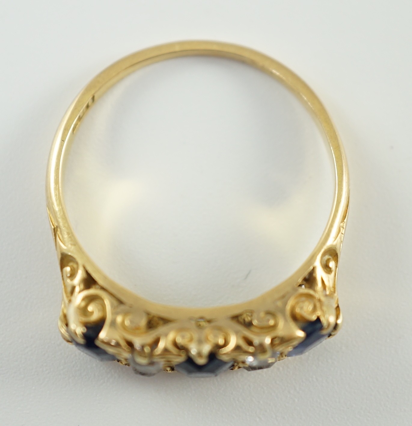 An early 20th century 18ct gold, three stone oval cut sapphire and four stone diamond spacer set half hoop ring